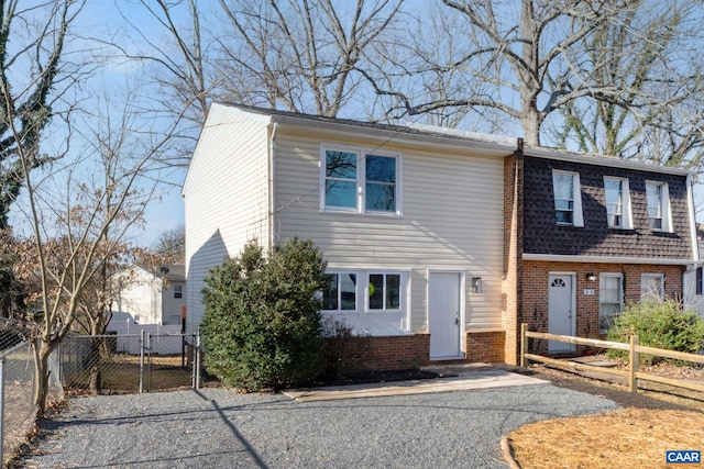 view of front of property featuring a gate, fence, and brick siding