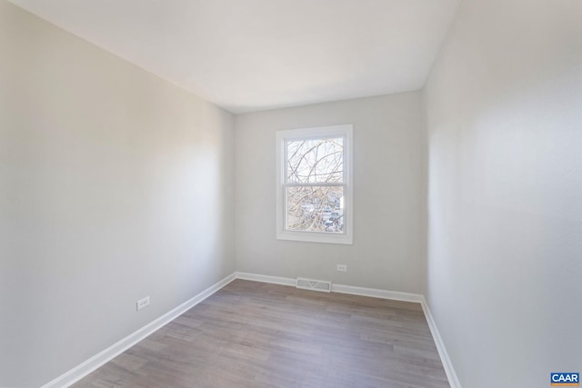 spare room with visible vents, baseboards, and wood finished floors