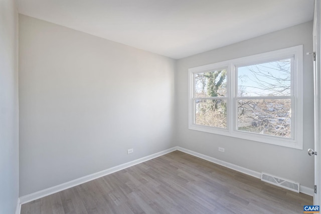 unfurnished room featuring visible vents, baseboards, and wood finished floors