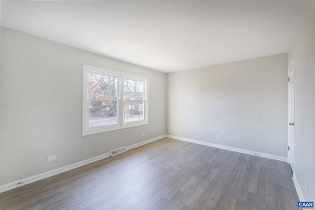 spare room featuring visible vents, baseboards, and wood finished floors