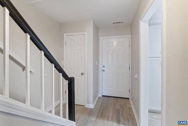 foyer with light wood finished floors, visible vents, and baseboards