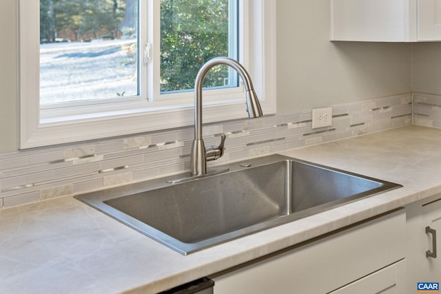 room details with white cabinetry, light countertops, and a sink