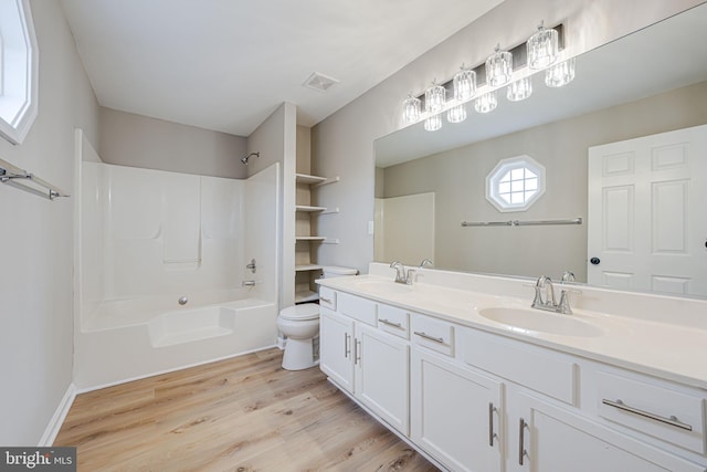 bathroom with visible vents, toilet, wood finished floors, and a sink