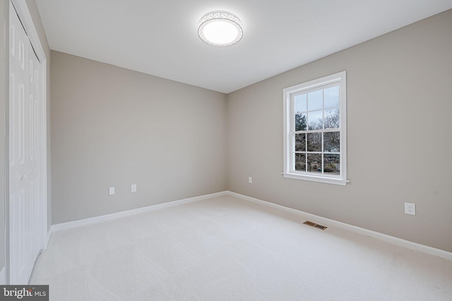 empty room featuring visible vents, light carpet, and baseboards