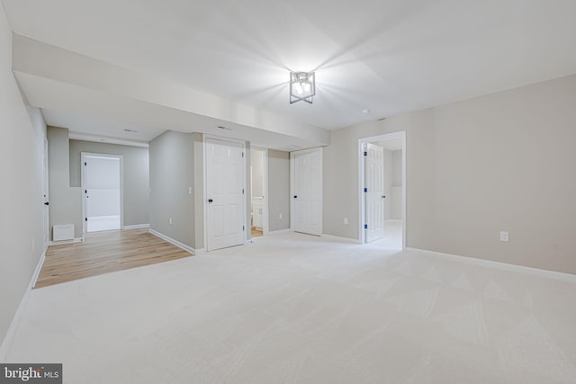 spare room with baseboards and light colored carpet