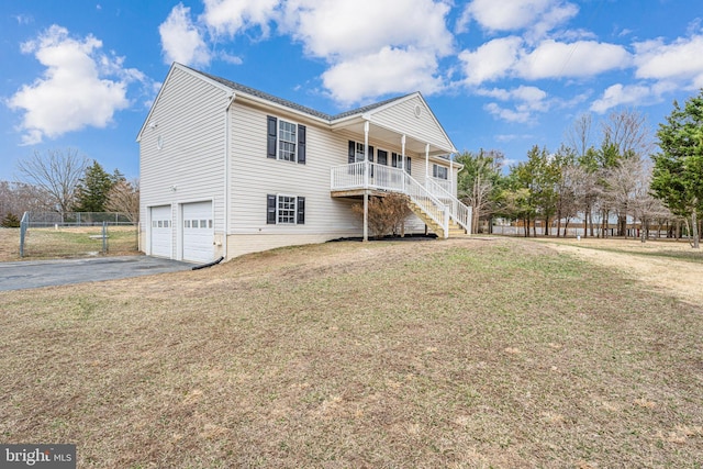 rear view of property with driveway, stairway, a yard, covered porch, and an attached garage