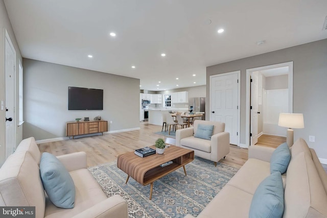 living room featuring recessed lighting, baseboards, and light wood-style floors