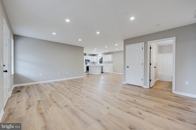 unfurnished living room with recessed lighting, baseboards, and light wood finished floors