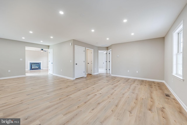 unfurnished living room with recessed lighting, light wood-type flooring, baseboards, and ceiling fan