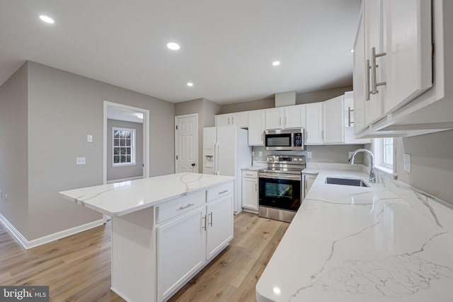 kitchen with light wood-type flooring, a sink, a kitchen island, stainless steel appliances, and white cabinets