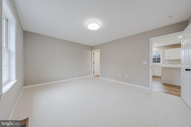 empty room featuring visible vents, baseboards, and light carpet