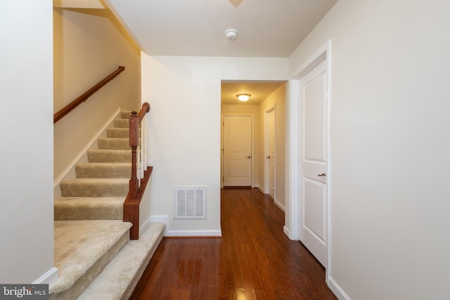 hallway with visible vents, stairs, baseboards, and wood finished floors