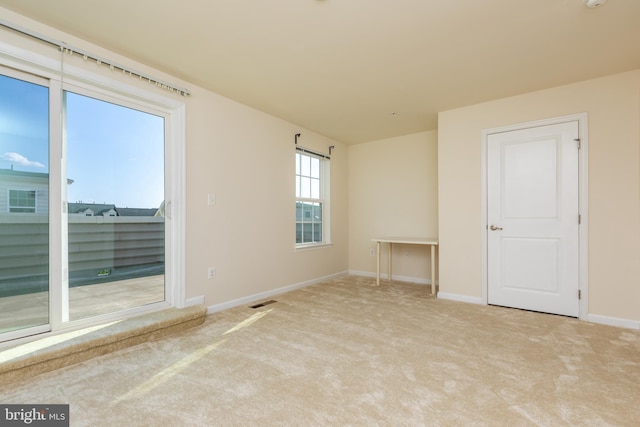 carpeted spare room with visible vents and baseboards