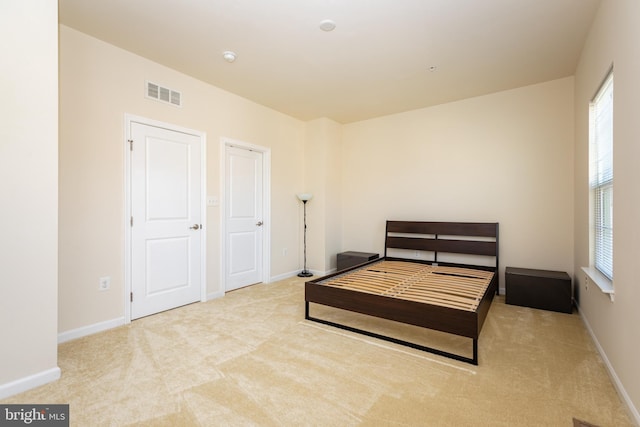 carpeted bedroom with visible vents, multiple windows, and baseboards