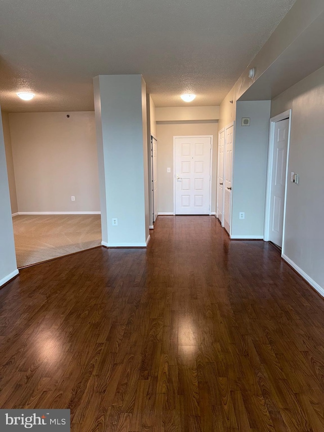 interior space featuring dark wood-style floors, baseboards, and a textured ceiling