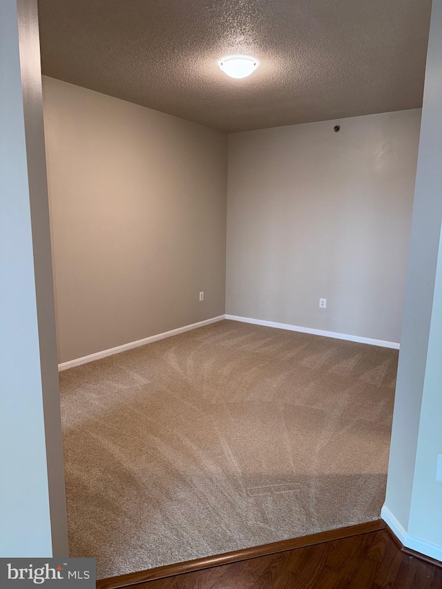 carpeted empty room featuring a textured ceiling and baseboards