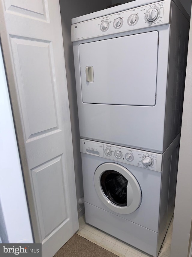 washroom featuring laundry area, light tile patterned flooring, and stacked washing maching and dryer