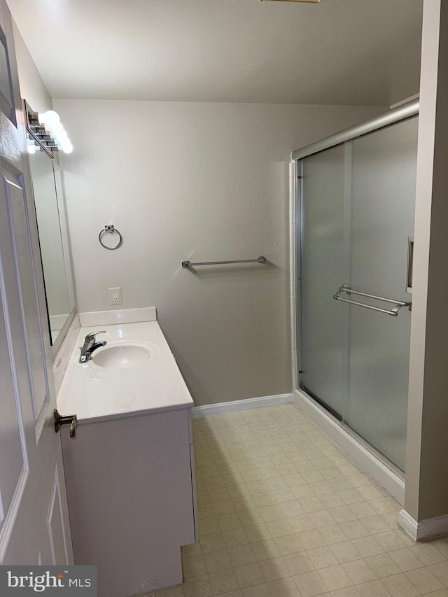 full bath featuring a stall shower, vanity, and baseboards