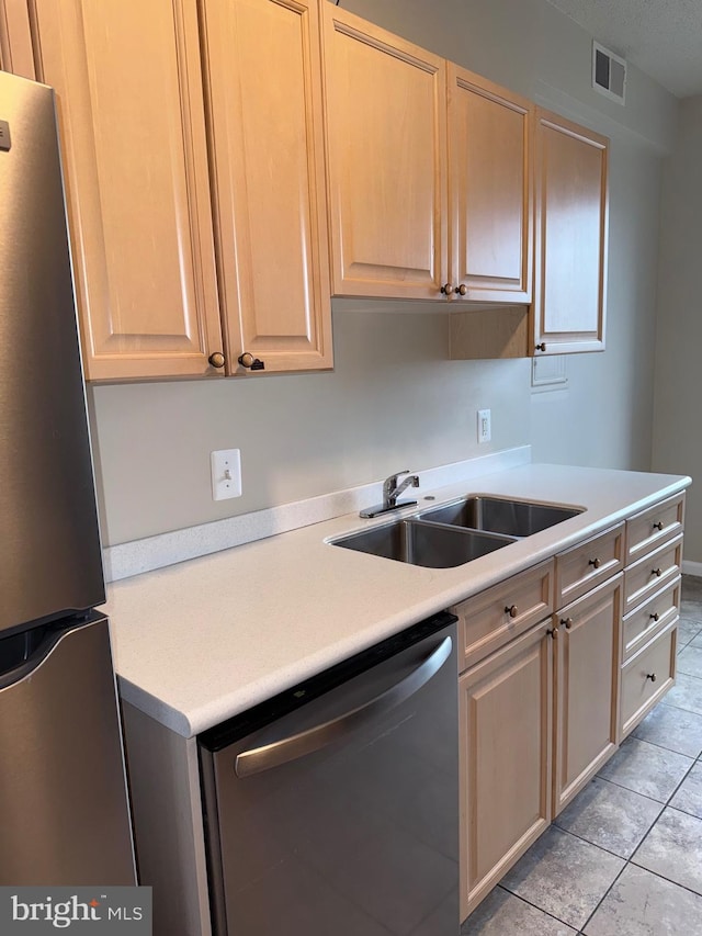 kitchen featuring visible vents, light countertops, light tile patterned floors, stainless steel appliances, and a sink