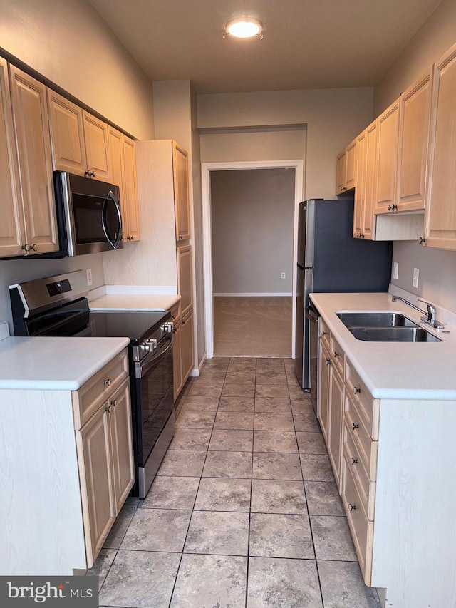 kitchen with light brown cabinets, light countertops, light tile patterned flooring, stainless steel appliances, and a sink