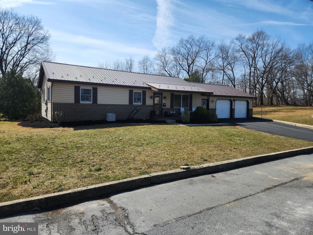 ranch-style home with aphalt driveway, a front yard, a garage, and metal roof