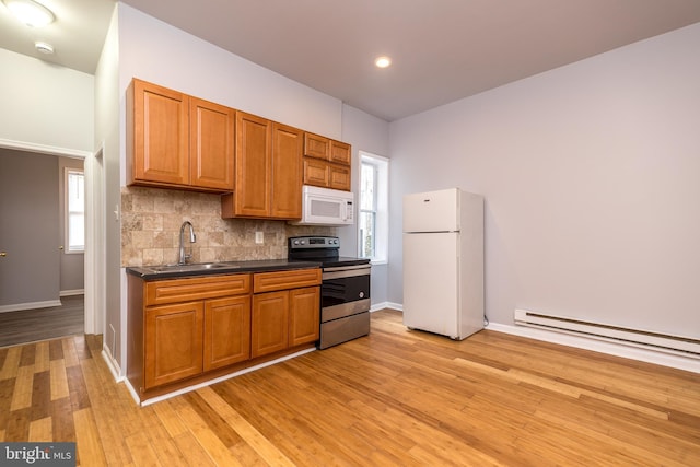 kitchen featuring brown cabinets, a sink, dark countertops, white appliances, and decorative backsplash