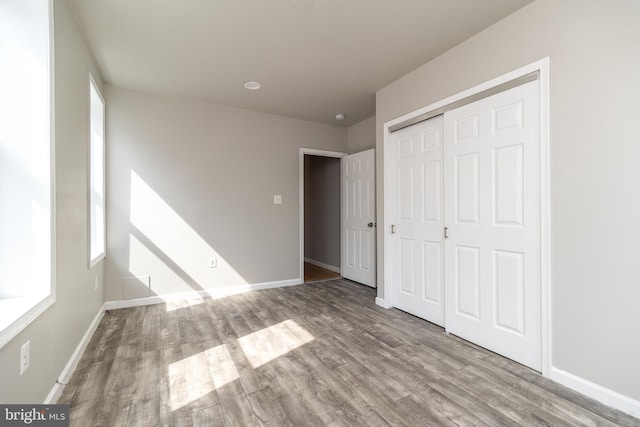 unfurnished bedroom featuring a closet, baseboards, and wood finished floors