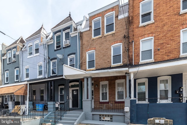 multi unit property featuring a porch, cooling unit, and brick siding