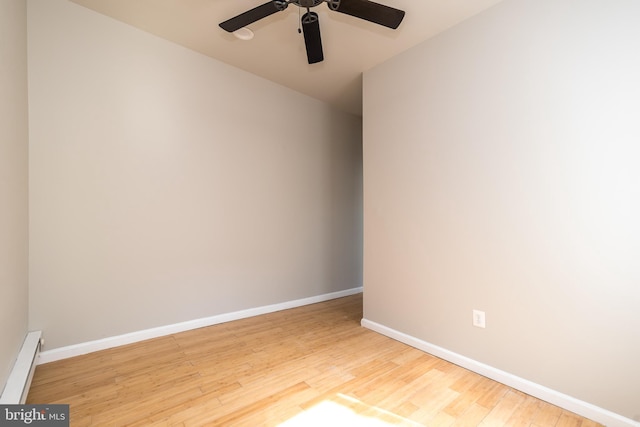 spare room with ceiling fan, a baseboard heating unit, baseboards, and wood finished floors