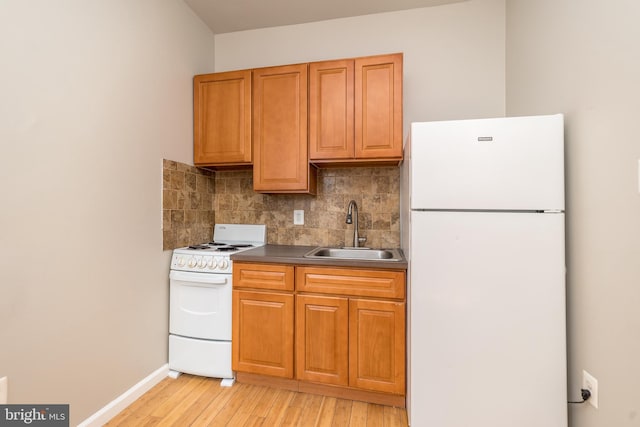 kitchen with white appliances, baseboards, a sink, decorative backsplash, and light wood-type flooring