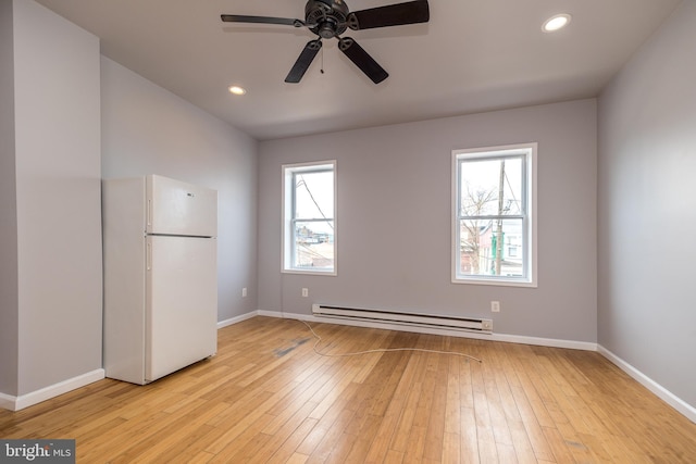 spare room featuring a wealth of natural light, recessed lighting, a baseboard heating unit, and light wood-style floors