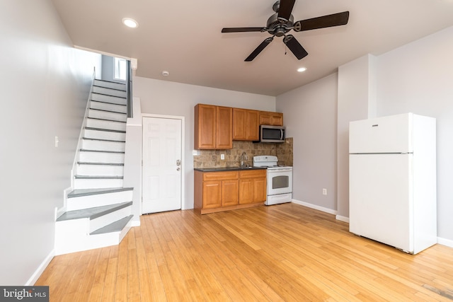 kitchen with tasteful backsplash, dark countertops, ceiling fan, light wood-style floors, and white appliances