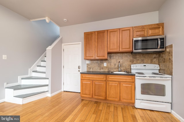 kitchen featuring light wood-type flooring, a sink, stainless steel microwave, tasteful backsplash, and white range with electric stovetop