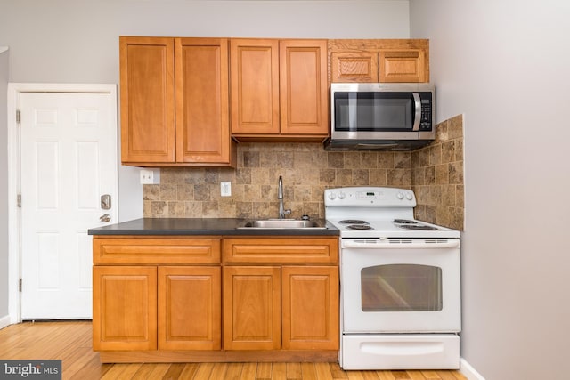 kitchen featuring dark countertops, a sink, decorative backsplash, stainless steel microwave, and white electric range