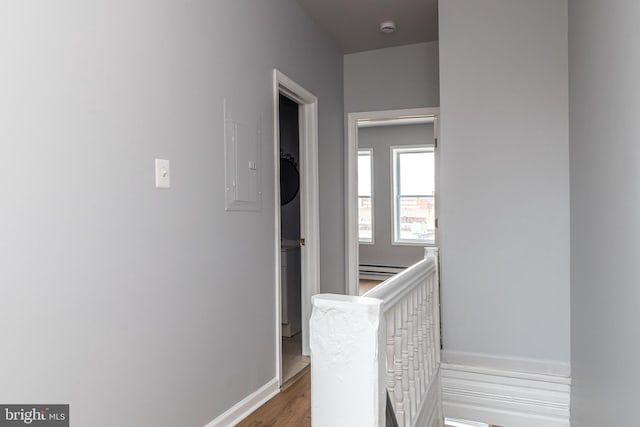 hall with stacked washer and dryer, wood finished floors, baseboards, and baseboard heating