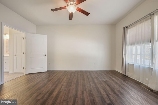 unfurnished room featuring dark wood finished floors, visible vents, baseboards, and a ceiling fan