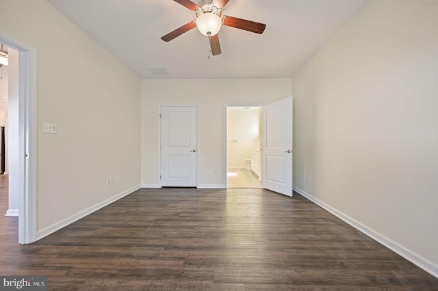 unfurnished bedroom featuring a ceiling fan, ensuite bath, dark wood-style floors, and baseboards