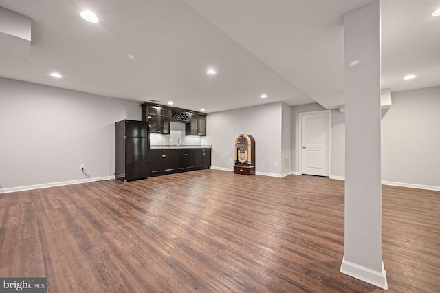 unfurnished living room featuring baseboards, wet bar, recessed lighting, dark wood-style flooring, and a sink