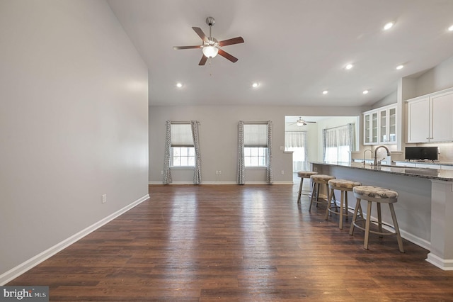 kitchen featuring white cabinetry, dark stone countertops, a kitchen breakfast bar, and ceiling fan