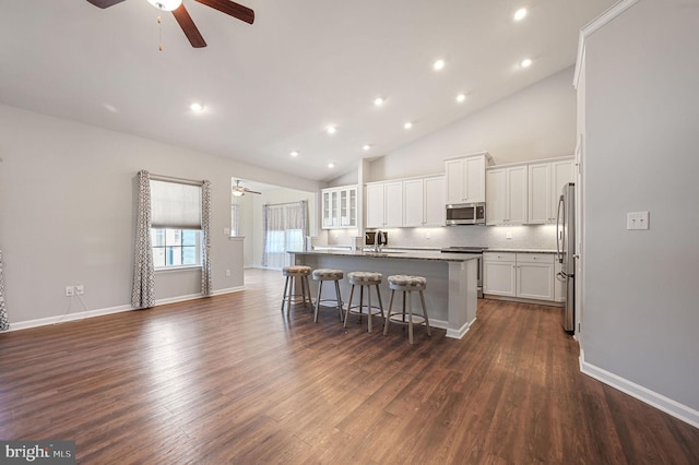 kitchen with ceiling fan, a kitchen breakfast bar, white cabinets, stainless steel appliances, and a sink