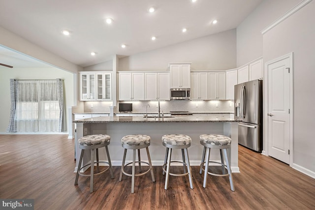 kitchen with a center island with sink, stone countertops, stainless steel appliances, and a sink