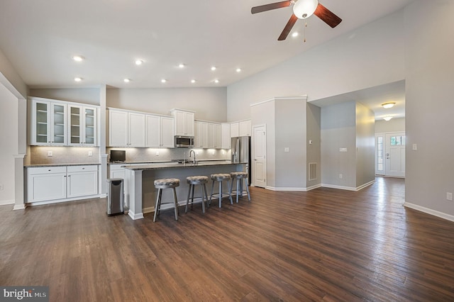 kitchen with visible vents, dark wood-type flooring, an island with sink, appliances with stainless steel finishes, and a kitchen breakfast bar