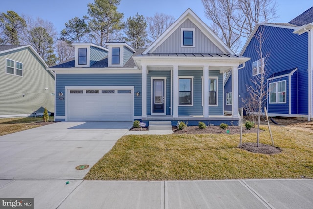 view of front of property with board and batten siding, a front yard, covered porch, a garage, and driveway