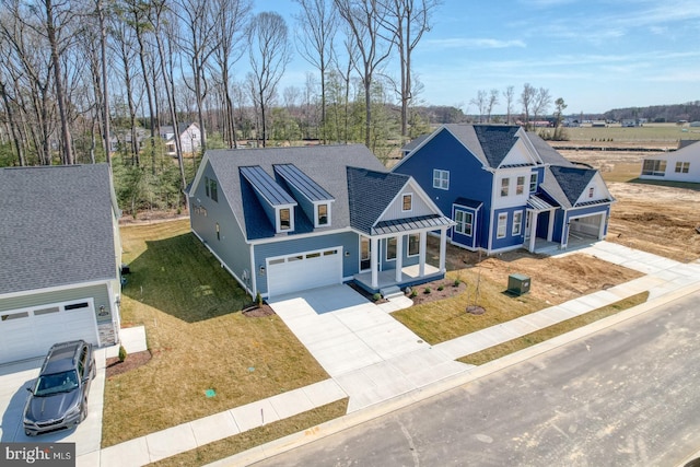 view of front facade with a garage, driveway, a standing seam roof, a front yard, and metal roof