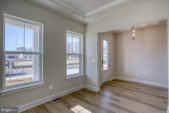 foyer entrance with a tray ceiling, wood finished floors, visible vents, and baseboards