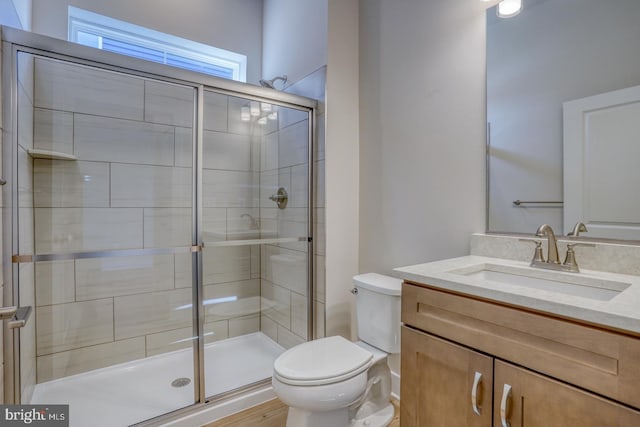 bathroom featuring a stall shower, toilet, and vanity