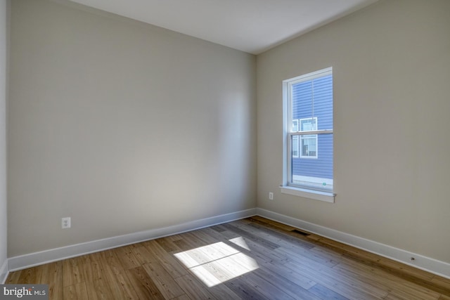 spare room featuring visible vents, baseboards, and wood finished floors