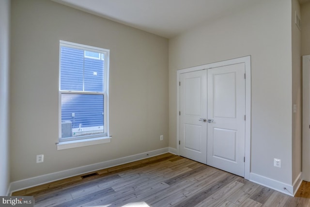 unfurnished bedroom with a closet, light wood-type flooring, and baseboards