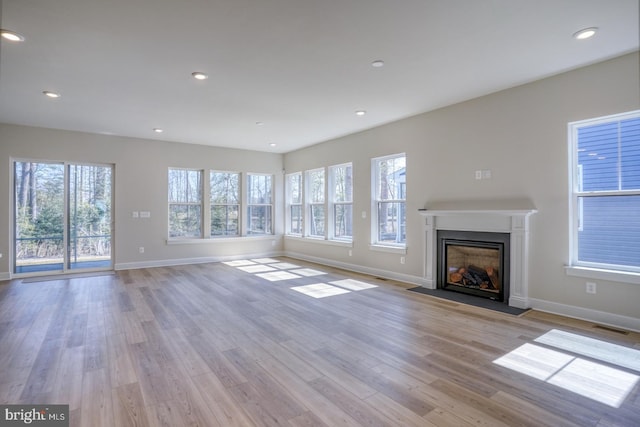 unfurnished living room featuring light wood-style flooring, plenty of natural light, and a fireplace