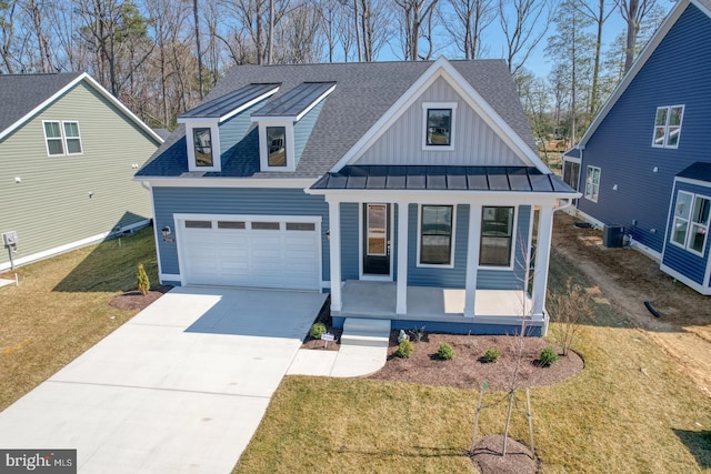 view of front of home with a front yard, cooling unit, covered porch, concrete driveway, and board and batten siding